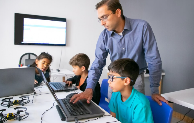 Instructor guiding students with laptops.