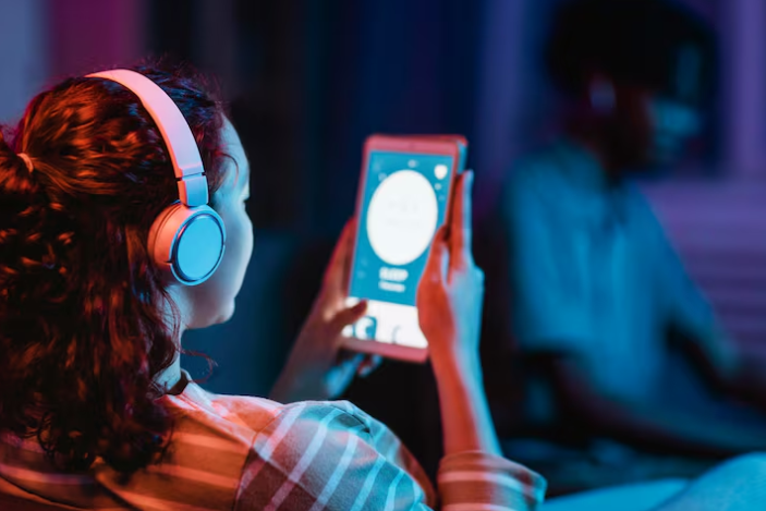 Girl with headphones holding tablet displaying music app interface.