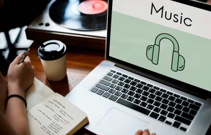 Laptop screen showing music icon beside notebook and vinyl player.