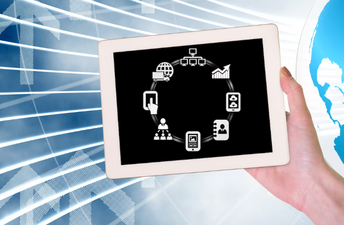 Hand holding tablet showing connected business and communication icons.