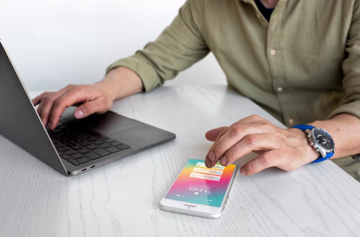 Man using laptop and smartphone together for automation and syncing.