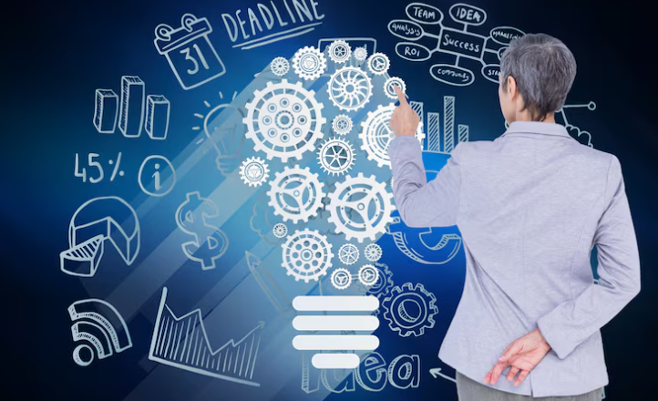 Businesswoman pointing at illuminated gears shaped like a light bulb.
