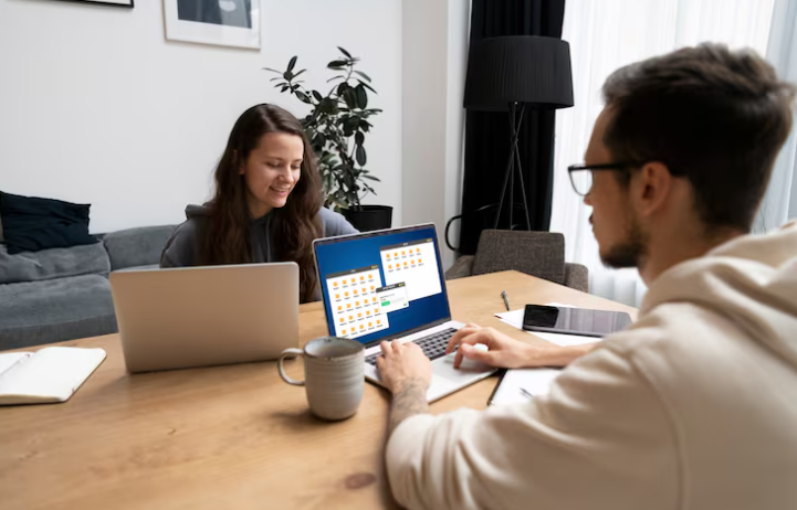 Two colleagues working together on laptops with file sharing displayed.