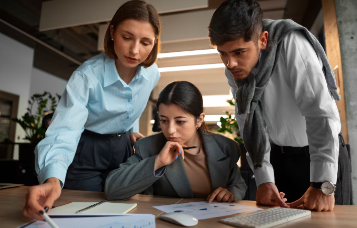 Three colleagues reviewing business documents together at modern office desk.