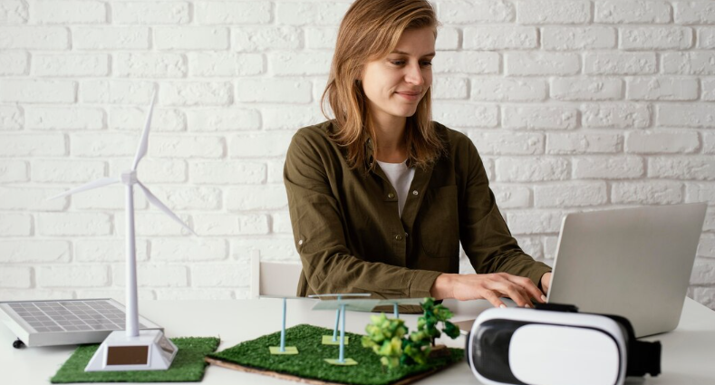 A woman working on a laptop with renewable energy models beside her.