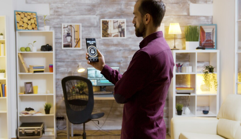 Man controlling smart home lighting through a mobile app and  Voice Assistant 