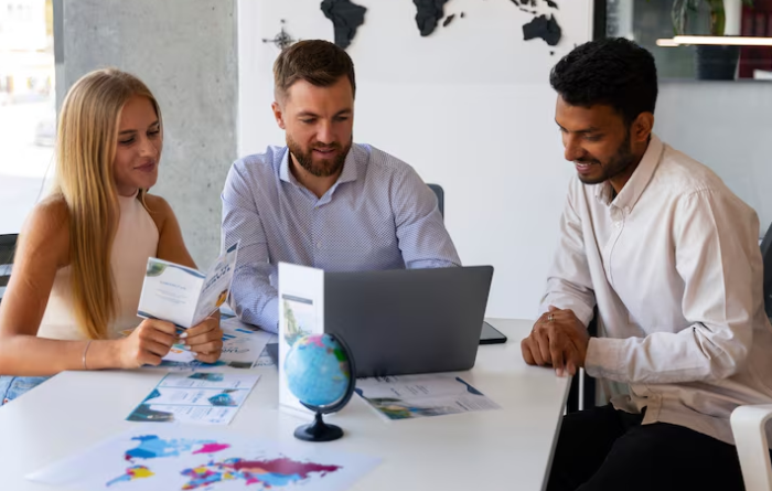 Three people discussing over a laptop.