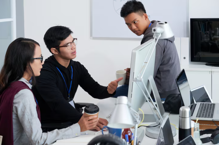 Team discussing ideas while working together on computers