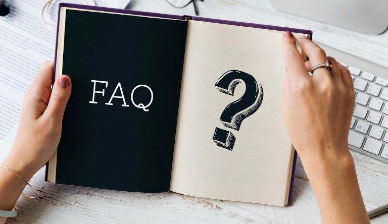 Close-up of open book with 'FAQ' on one page and a large question mark on the other.