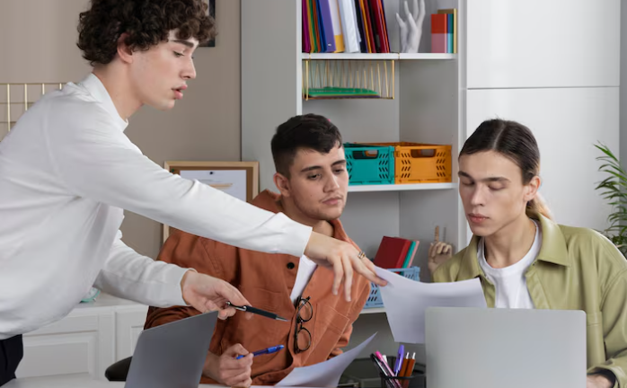 Group of young professionals collaborating in an office, reviewing design documents together.