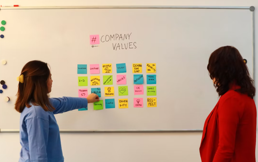Two women discussing company values board