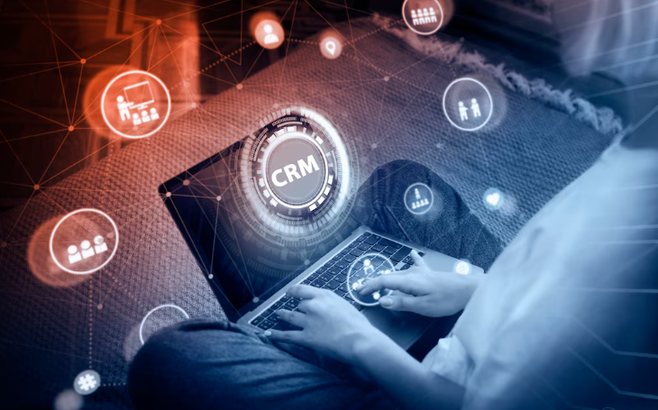 User on laptop with glowing CRM hologram and digital icons.