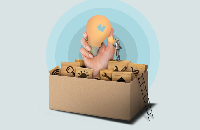 Hand holding light bulb above box