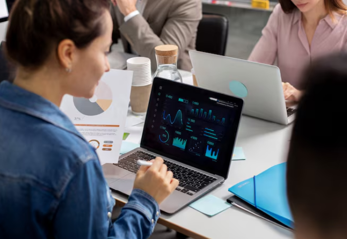 Businesswoman analyzing data dashboard on laptop during office meeting.