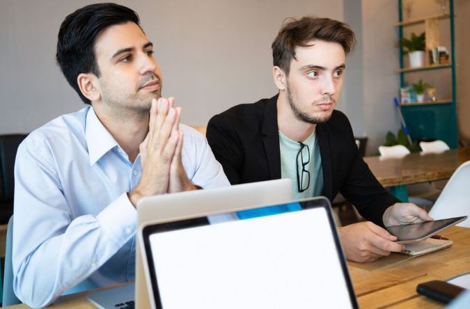 Two colleagues attentively listening during office meeting.