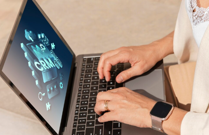 Person using laptop with CRM software on screen.