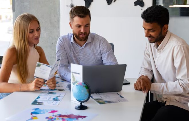 Business team discussing global project around laptop and brochures.