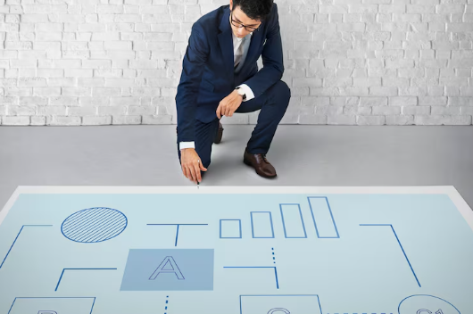 Businessman planning project workflow on large floor diagram.
