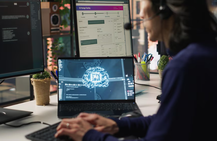 Someone wearing a headset working on a laptop with AI/automation visuals on the screen.