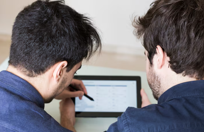 Two individuals looking at a digital interface on a tablet, likely discussing automation or data workflows.