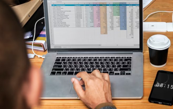 Man analyzing financial data in colorful spreadsheet on laptop screen.