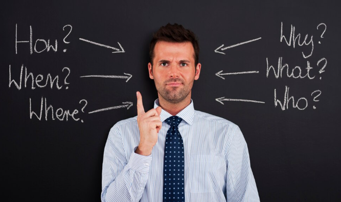 Businessman pointing upward surrounded by chalkboard arrows with critical questions.