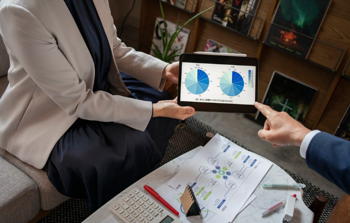 Business professionals analyzing charts on tablet during discussion.
