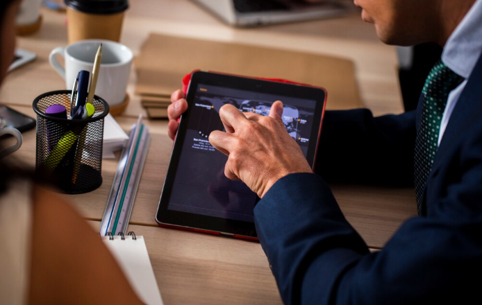 Businessman using tablet during meeting with documents and office supplies.