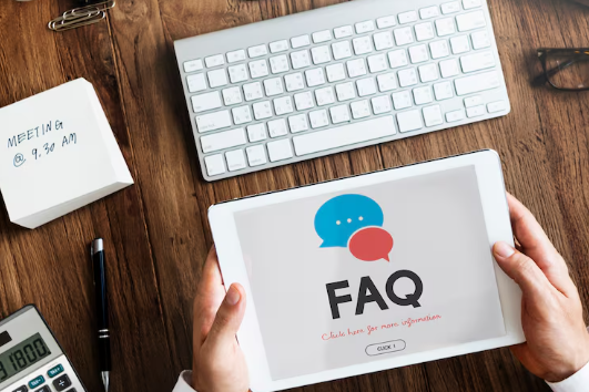 Person holding tablet displaying FAQ page on wooden desk.