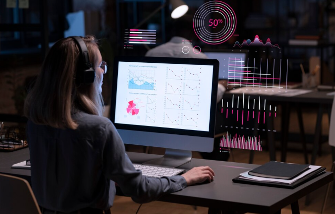 Woman using computer with digital analytics and data visualization.