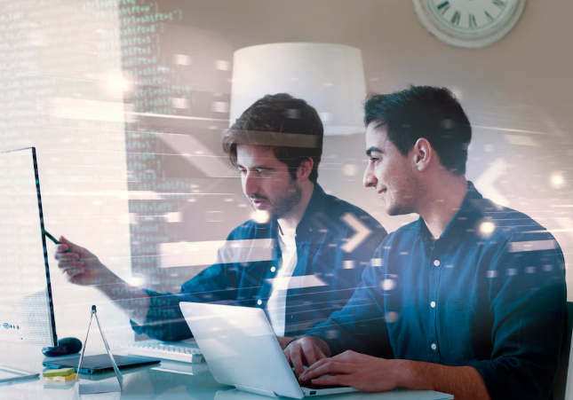 Two men collaborating on code while looking at a monitor.