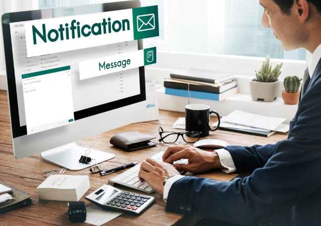 Businessman checking email notification on desktop computer at office desk.