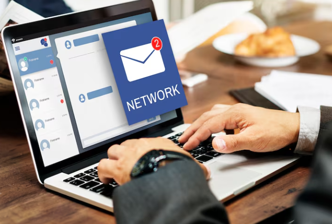 Person typing on laptop with new network email notification popup.