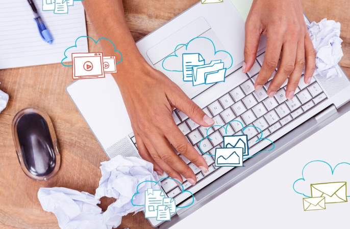Hands typing on laptop keyboard with digital cloud storage icons.