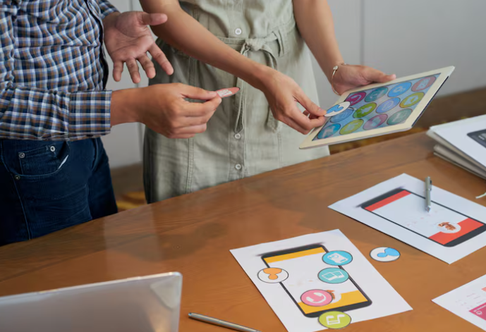 Team discussing mobile app icons and interface design on tablet.