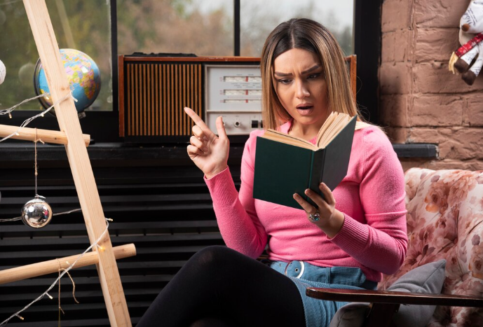 Surprised woman reading a book and pointing with finger.