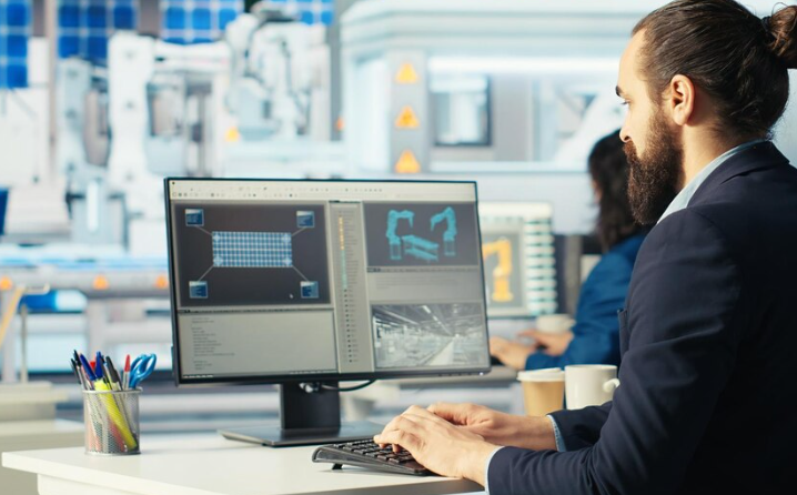 Engineer designing robotic machinery model on desktop computer screen.