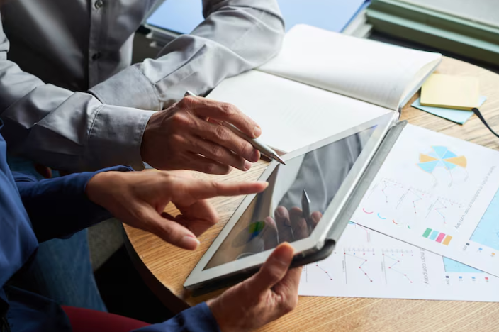 Close-up of hands analyzing data charts on a tablet.