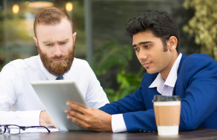 Two businessmen discussing project details using a digital tablet.