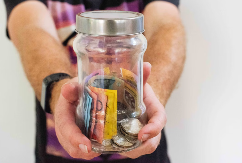 Hands holding a glass jar filled with coins and cash and Non-Profit Built a Donor Management App with No-Code .