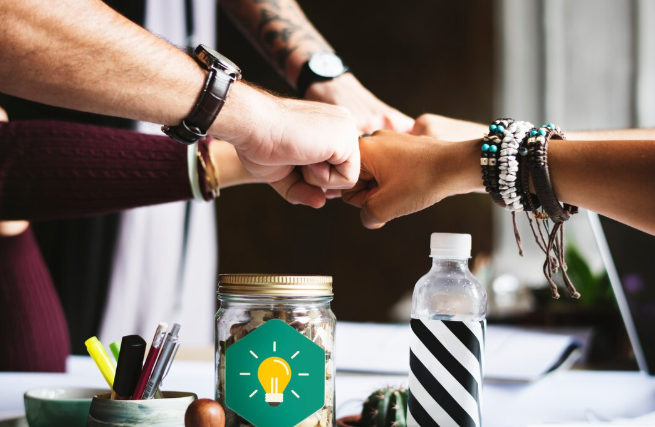 Team members doing fist bump together over a table.