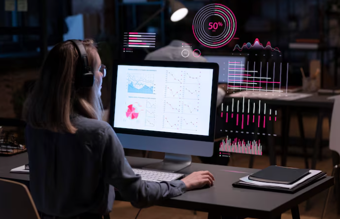 Woman analyzing graphs and data on computer with digital overlay.