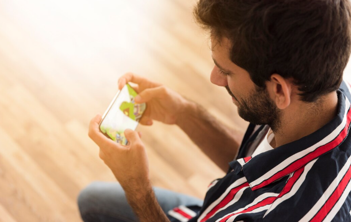 Person playing a mobile game and Build Your Mobile Game Without Writing a Single Line of Code