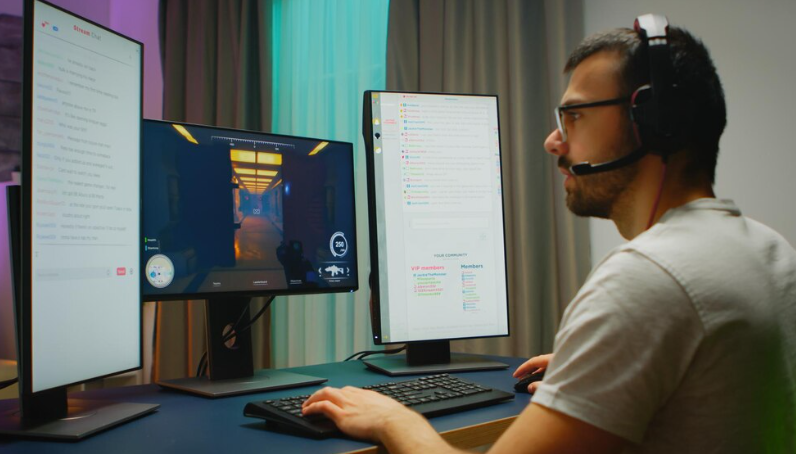 Person gaming with dual monitors setup.