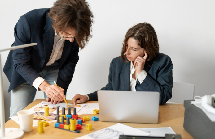 Two professionals discussing at a desk.